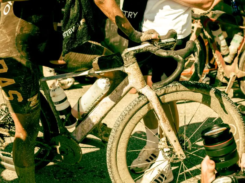 Cyklister med leriga gravelcyklar i depån efter ett tävlingslopp